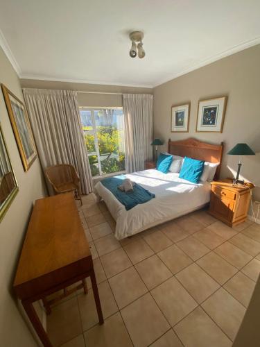 a bedroom with a bed and a table and a window at Goose Valley Unit EE4 in Plettenberg Bay