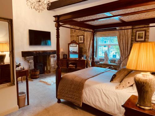 a bedroom with a canopy bed and a fireplace at Busfeild Arms in Keighley