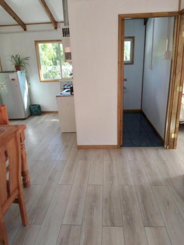 a living room with a wooden floor and a kitchen at Calfu in Chile Chico