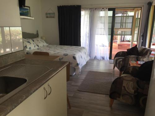 Studio at Matarangi في وايتيانغا: مطبخ وغرفة معيشة مع سرير وغرفة نوم
