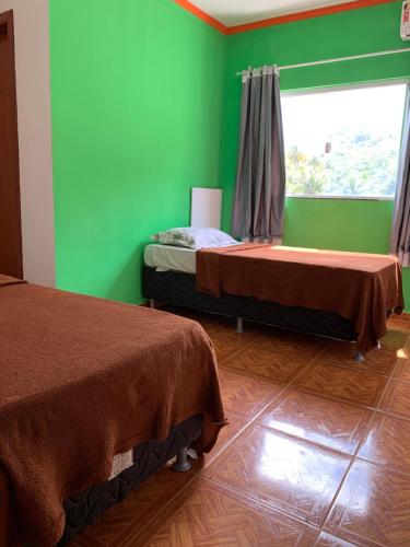 a room with two beds and a green wall at Pousada estância gaúcha in Guarapari