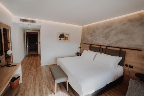 um quarto com uma cama branca e uma cadeira em Böden Hotel & Spa by AKEN Soul em Villa General Belgrano