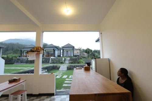 a woman sitting at a large wooden table in a house at Bali Astetic Villa and Hot Spring in Kintamani