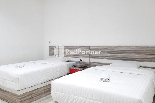 two beds in a room with a sign on the wall at Roemah Proklamasi Syariah Mitra RedDoorz in Kampungdurian