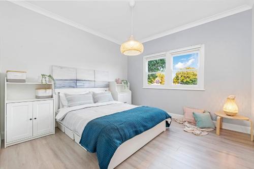 a white bedroom with a large bed and a window at 2 Min Walk to Beach Firepit Yard Kids welcome in Ettalong Beach