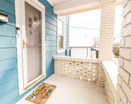 une porte d'entrée d'une maison bleue avec un tapis sur la terrasse couverte dans l'établissement Cozy Riverfront Bungalow with Stunning Views, à Covington