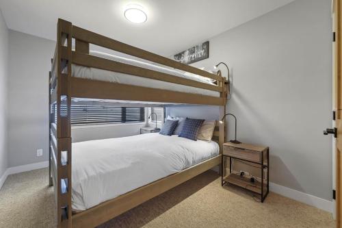 1 dormitorio con litera con sábanas blancas y almohadas azules en Zola Retreat- RARE Luxury Ski in/out *Hot tub, BBQ, Double heated garage* en Sun Peaks