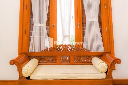 a bench in front of a window with curtains at RedDoorz at Daffi Araya in Malang