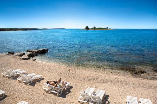 a group of lawn chairs and people laying on a beach at Maistra Select Villas Rubin Resort in Rovinj