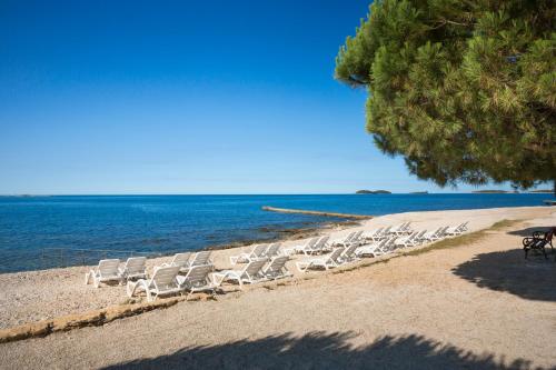 een groep stoelen op een strand bij het water bij Maistra Select Villas Rubin Resort in Rovinj