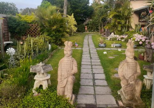 un jardin avec des statues de personnes assises sur un chemin dans l'établissement Vincentia Odd Cottage ( self catering), à East London