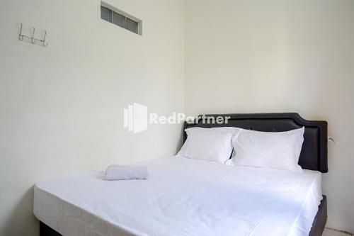 a white bed with a black headboard and white pillows at Pringgondani Guest House At Pandanaran Hills Semarang in Semarang