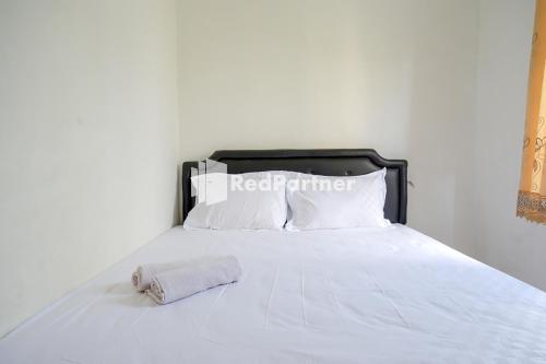 a white bed with a black headboard and white pillows at Pringgondani Guest House At Pandanaran Hills Semarang in Semarang