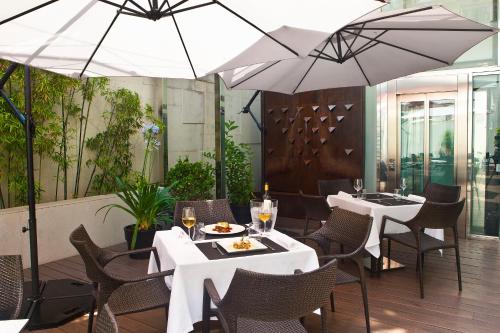 a restaurant with white tables and chairs and umbrellas at Grupotel Gran Via 678 in Barcelona