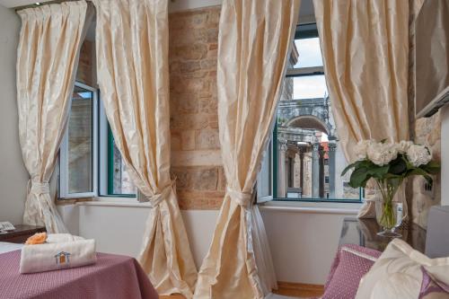 a white table topped with white curtains next to a window at Heritage Hotel Antique Split in Split