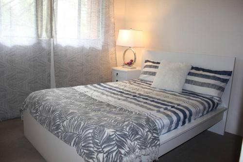 a bedroom with a bed and a lamp and a window at Macquarie Treetops - Sydney 2BR Apt with FREE parking at Macquarie Park in Sydney
