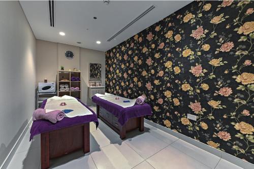 a room with two beds and a wall with flowers at TIME Asma Hotel in Dubai