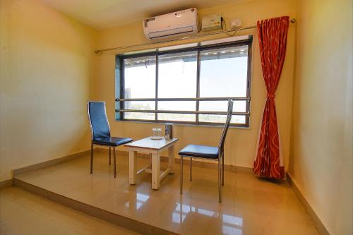 a room with two chairs and a table and a window at Shivneri Holiday Resort in Mahabaleshwar