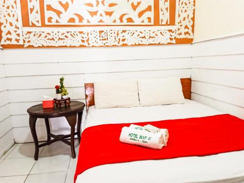 a bed with a red blanket next to a table at Hotel 41 Maribaya in Tegal