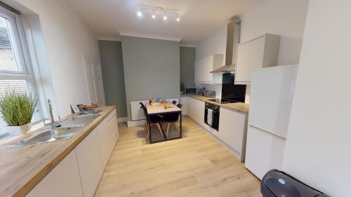 a kitchen with white cabinets and a table in it at Station House By Horizons Stays in Darlington
