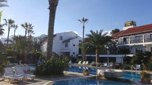 a resort with a swimming pool and palm trees at Topset Hotel in Kérynia