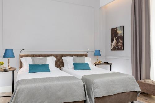 two beds in a hotel room with blue pillows at Hotel La Ville Rome in Rome