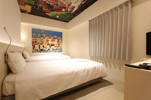 a bedroom with a white bed with a painting on the wall at KOKO HOTEL Osaka Namba Ebisucho in Osaka