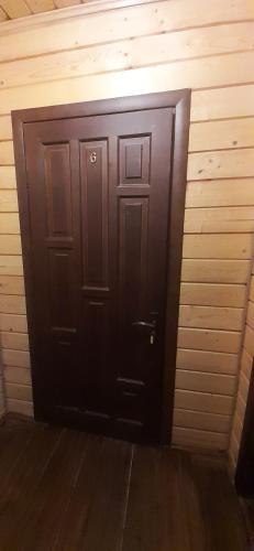 a black door in a room with a wooden wall at Біла хата in Iltsi