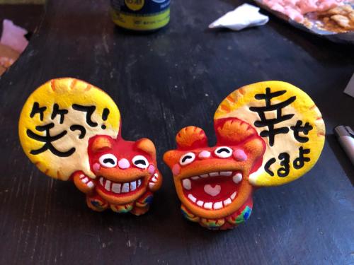 two figurines with chinese writing on them on a table at Happy Island Miyako in Miyako Island
