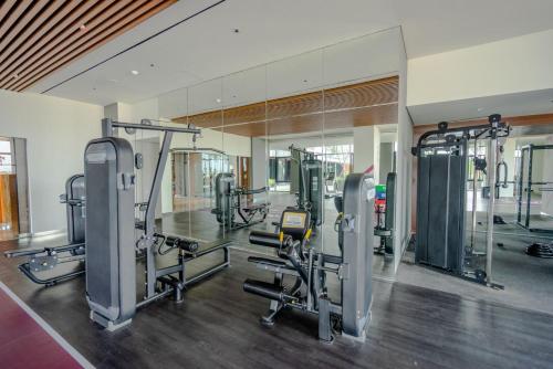 un gimnasio con varias máquinas de correr y un espejo en EMKA Lodge studio room the vertu apartemen ciputra world surabaya en Surabaya