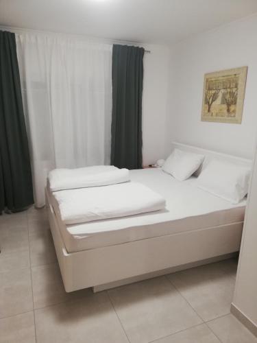 two white beds in a room with green curtains at Sobe Šušanj in Karlobag