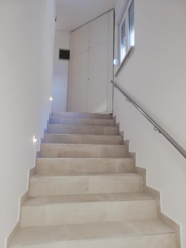 a staircase in a house with white walls and concrete stairs at Sobe Šušanj in Karlobag