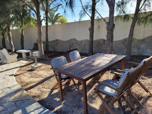 a wooden table and chairs with trees in the background at Fuerte Action Guest House in Costa Calma