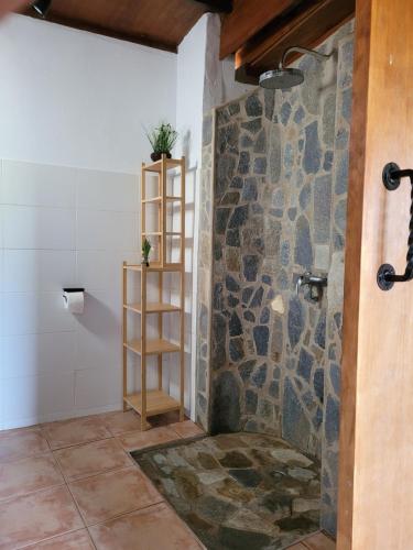 a bathroom with a shower with a stone wall at Fuerte Action Guest House in Costa Calma