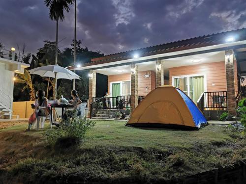 a tent sitting in the grass in front of a house at เฮือนป้อหลวง in Ban Fang
