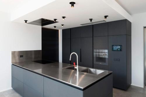 une cuisine avec des placards noirs et un évier en acier inoxydable dans l'établissement Ca' de Sass near Argegno Lake Como, à Colonno