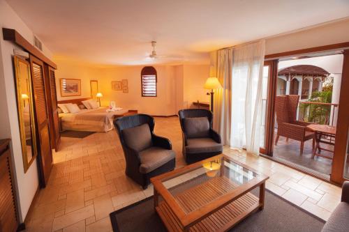 ein Wohnzimmer mit Stühlen, einem Bett und einem Tisch in der Unterkunft Le Saint Alexis **** Hotel & Spa in Saint-Gilles-les-Bains