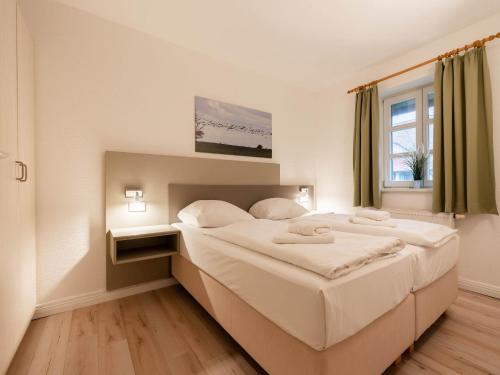 a bedroom with a large white bed and a window at Feriendorf Rugana - Komfort Appartement mit 1 Schlafzimmer und Terrasse B16 in Dranske