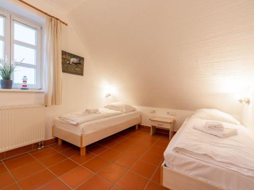 zwei Betten in einem kleinen Zimmer mit Fenster in der Unterkunft Feriendorf Rugana - Klassik Appartement mit 2 Schlafzimmern und Terrasse D01 in Dranske