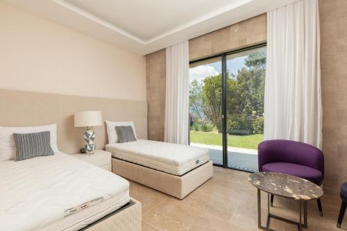 a bedroom with a bed and a chair and a window at Villa Mandragora in Kotor