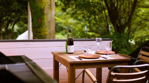 Una botella de vino sentada en una mesa de madera con copas en Tokitama Himitsumichi COMORIVER - Vacation STAY 43686v, en Banshō