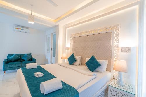 a bedroom with a large bed and a blue chair at Lillywoods Zac Beach Resort, Calangute in Goa Velha