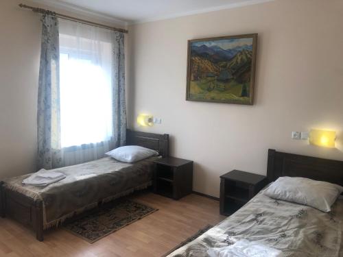 two beds in a room with a window and a painting at Europa in Rakhiv