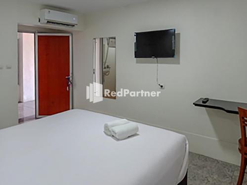 Schlafzimmer mit einem Bett, einem Schreibtisch und einem TV in der Unterkunft Hotel Trikatu Kendal near Taman Kota Weleri Mitra RedDoorz in Kendal