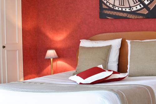 a bedroom with a white bed with a red wall at Logis Hôtel-Restaurant Le Relais in Hauterives