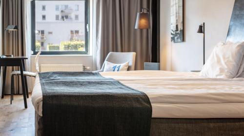 a hotel room with a bed and a desk and a window at Quality Hotel 11 & Eriksbergshallen in Gothenburg