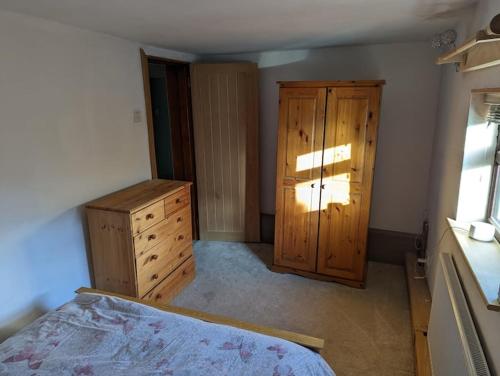 a bedroom with a bed and a wooden cabinet at Beautiful rural cottage with secure garden in Bradley