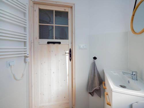 a bathroom with a wooden door next to a sink at Szum Fal in Rusinowo