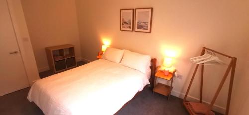 een slaapkamer met een wit bed en 2 lampen bij Apartment one Estuary Reach in Exmouth