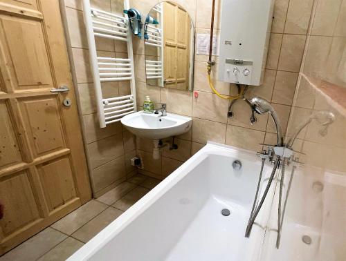 a bathroom with a bath tub and a sink at Évi Apartman in Eger